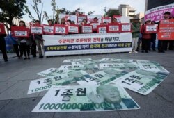 FILE - Fake bank notes showing images of U.S. President Donald Trump are displayed as protesters oppose the United States' demand for raising the defense costs for stationing U.S. troops in South Korea, near the U.S. embassy in Seoul, Oct. 22, 2019.