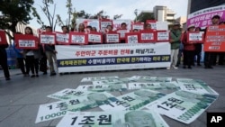 FILE - Fake bank notes bearing U.S. President Donald Trump’s image are displayed as protesters rally against the United States' demand for raising the defense costs for stationing U.S. troops in South Korea, near the U.S. embassy in Seoul, Oct. 22, 2019.