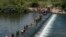 Migran Haiti menyeberangi bendungan dari Meksiko untuk memasuki Del Rio, Texas, Amerika Serikat, Sabtu, 18 September 2021. (AP Photo/Eric Gay)