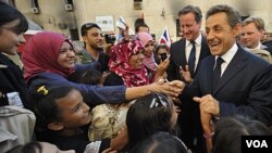 PM Inggris David Cameron (tengah) dan Presiden Perancis Nicolas Sarkozy dielu-elukan oleh massa yang menyalami mereka di Benghazi (15/9).