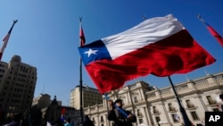 Un trabajador de la empresa siderúrgica chilena Huachipato ondea una bandera chilena frente al palacio presidencial de La Moneda el martes 9 de abril de 2024.
