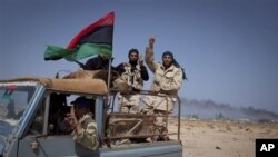 Libyan rebels gesture as they pass the oil refinery in the outskirts of Ras Lanouf, eastern Libya, Sunday, March 27, 2011. Libyan rebels took back a key oil town and pushed westward Sunday toward the capital, seizing momentum from the international airst