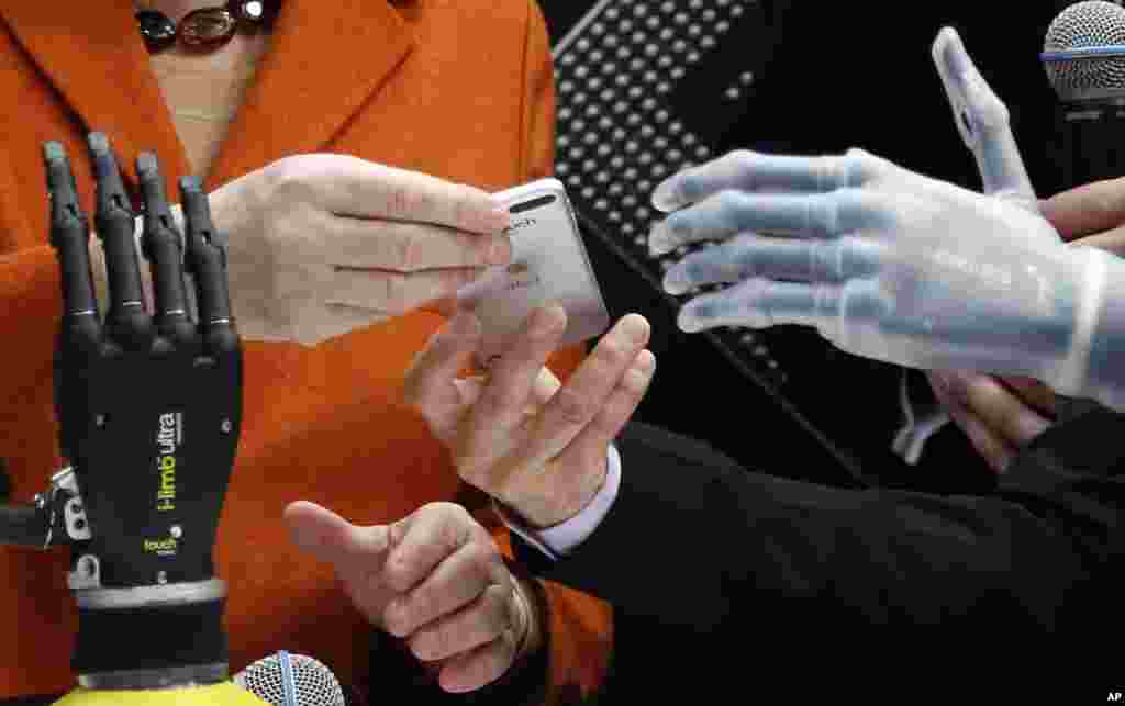 The hands of Claudia Breidbach, right, demonstrating her bionic hand that is steerable by a mobile phone or iPod via Bluetooth to German Chancellor Angela Merkel, left, and British Prime Minister David Cameron during the opening day of the computer fair CeBIT in Hannover, Germany.