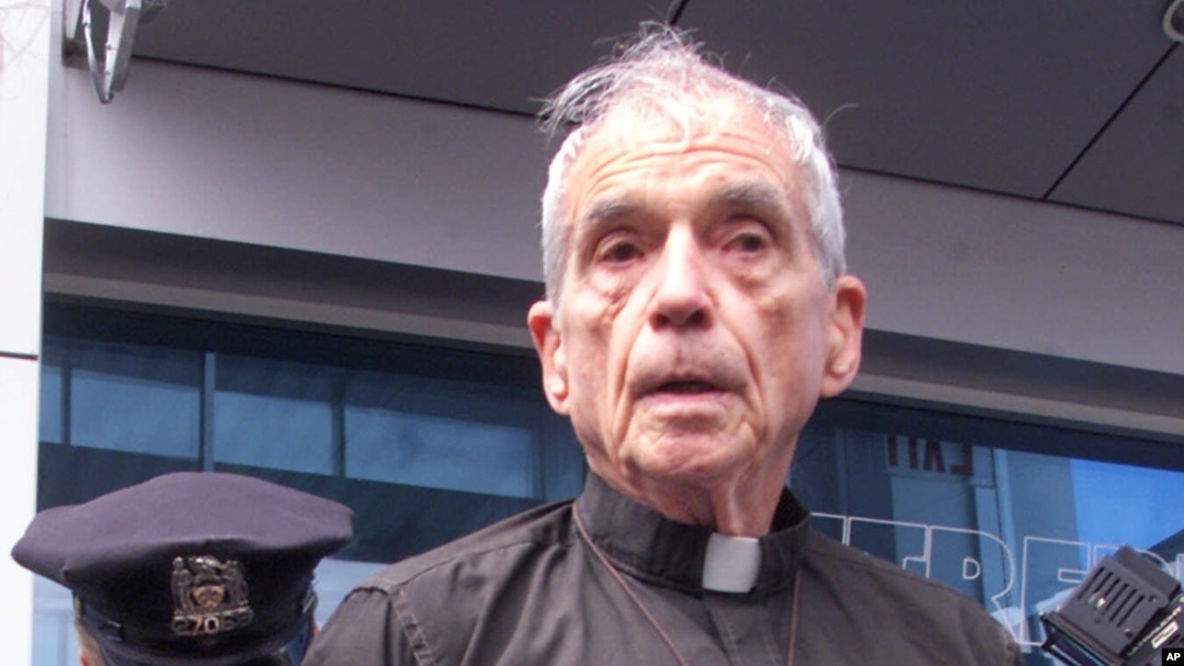 FILE - The Rev. Daniel Berrigan is handcuffed by a New York City Police officer in front of the Intrepid Sea-Air-Space Museum in New York, after he and others blocked an entrance to the venue, April 13, 2001. Berrigan died Saturday at the age of 94. 