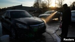 A man washes a car at a small corner carwash in Selma, Ala., Dec. 16, 2017. In Britain hand car washes are often reported for alleged labor abuses and may be regulated in an attempt to stop modern-day slavery.