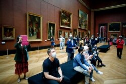 Visitors watch oil on canvas of 1807 entitled Le Sacre de Napoleon by Jacques Louis David, at the Louvre Museum, in Paris, July 6, 2020.