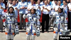 Chinese astronauts (from L to R) Wang Yaping, Zhang Xiaoguang and Nie Haisheng wave before leaving for the Shenzhou-10 manned spacecraft mission at Jiuquan satellite launch center in Jiuquan, Gansu province, June 11, 2013. 