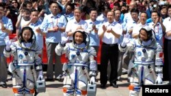 Astronot China (dari kiri) Wang Yaping, Zhang Xiaoguang dan Nie Haisheng melambaikan tangan sebelum memasuki pesawat antariksa Shenzhou-10 di pusat peluncuran pesawat di Jiuquan, propinsi Gansu (11/6).