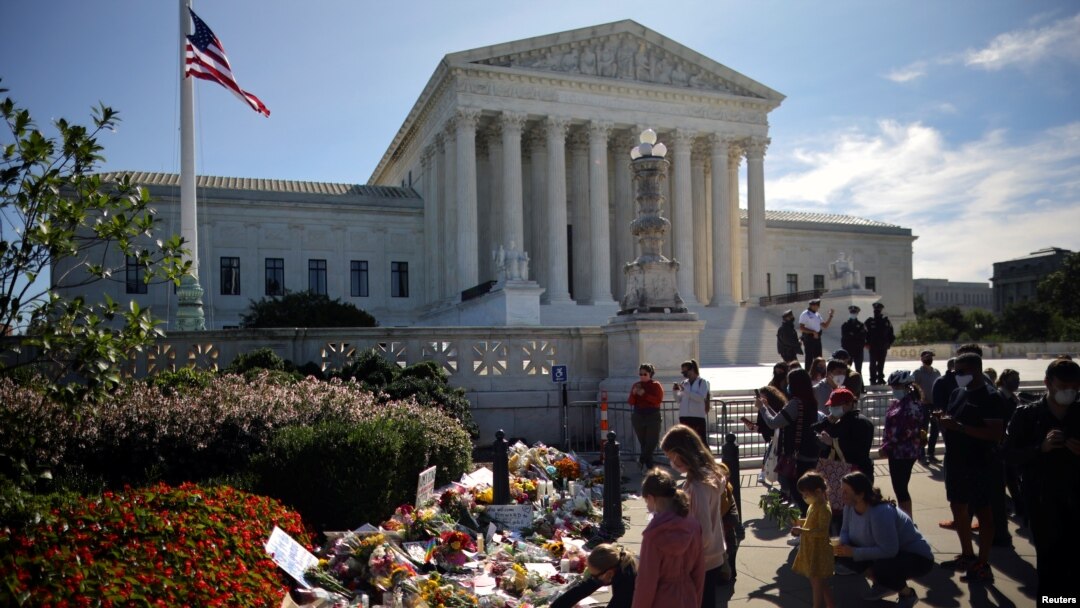  A woman puts flower on a memorial altar as people gather in front of the U.S. Supreme Court following the death of U.S. Supreme Court Justice Ruth Bader Ginsburg, in Washington, U.S., September 19, 2020. REUTERS/Carlos Barria