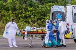 FILE - Medical staff carry a patient infected with the novel coronavirus into an Airbus A400M at Guiana air base 367 in Matoury, near Cayenne, in the French overseas department of Guiana, June 28, 2020.