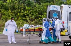 FILE - Medical staff carry a patient infected with the novel coronavirus into an Airbus A400M at Guiana air base 367 in Matoury, near Cayenne, in the French overseas department of Guiana, June 28, 2020.