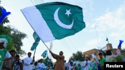 FILE - A man from the Pakistan's Hindu community waves a national flag during a rally expressing solidarity with the people of Kashmir, in Peshawar, Pakistan, Aug. 14, 2019.