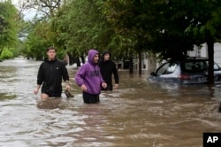 People wade through a flooded street after a storm in Bahia Blanca, Argentina, March 7, 2025.