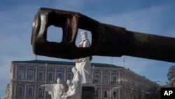 Un monumento de la Gran Princesa Olga del siglo X, con un chaleco antibalas simulado, se ve a través de un cañón de tanque de vehículos militares rusos destruidos exhibidos en la plaza Mykhailivska en el centro de Kiev, Ucrania, el 22 de octubre de 2024.