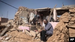 FILE - A man who lost his wife and daughter in the earthquake, sits in what used to be his home, in the town of Amizmiz, outside Marrakech, Morocco, on September 14, 2023.