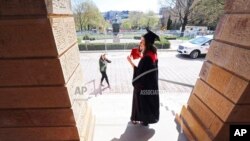 In this May 7, 2020 photo University of Wisconsin-Madison 2020 graduate Sara Krueger poses for photographs with her mother, Teri, on the steps of Bascom Hall in Madison, Wis. 