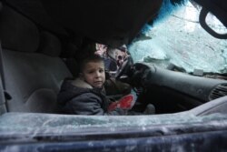 FILE - A boy, sitting in a car, cries following airstrikes by government forces, in the town of Ariha, in Idlib province, Syria, Jan. 15, 2020.