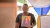 FILE— Winnie Akinyi, elder sister to Rose Bella Awuor, holds her late sister's portrait in Awendo, Migori County, Kenya April. 11, 2024. 
