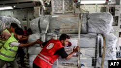 FILE - An Egyptian Red Crescent member and other workers unload a shipment of humanitarian aid bound for the Gaza Strip at Arish International Airport in North Sinai province in northeastern Egypt on November 9, 2023.