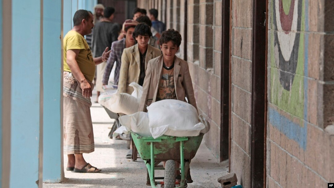 Warga Yaman menerima bantuan makanan dari Badan Pangan Dunia, di sebuah sekolah di Sanaa, Yaman, 25 Agustus 2019. (Foto: AP)