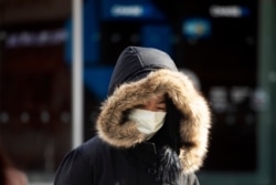 FILE - A woman, who declined to give her name, wears a mask, in New York City, Jan. 30, 2020. She works in a doctor's office and said she wears the mask "partly" out of concern over the coronavirus.