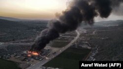 An aerial view of a billowing smoke plume coming from burning trucks and freight vehicles in the aftermath of Russian air strikes at a depot near the Bab al-Hawa border crossing between Syria and Turkey in Syria's rebel-held northwestern Idlib province, March 21, 2021.