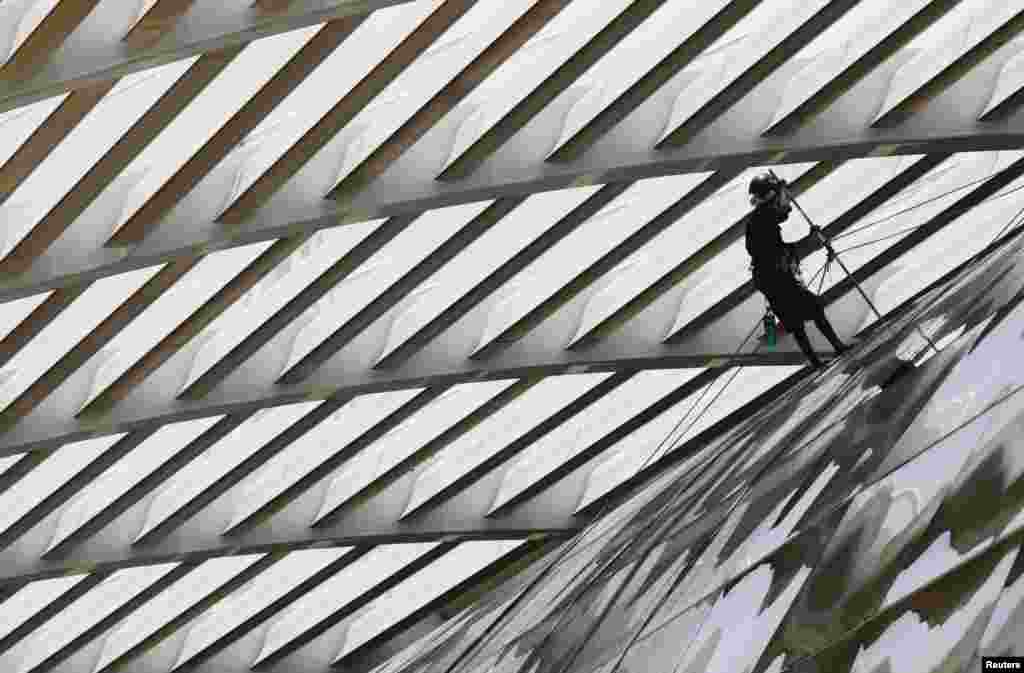 A worker cleans the glass facade of a mall in Singapore.