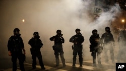 Federal officers are surrounded by smoke as they push back demonstrators during a Black Lives Matter protest at the Mark O. Hatfield United States Courthouse in Portland, Oregon, July 29, 2020.
