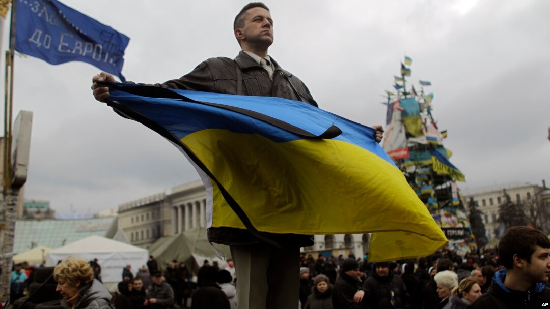 Seorang demonstran anti-pemerintah Yanukovych memegang bendera Ukraina di Lapangan Merdeka, Kyiv, Ukraina (25/2).