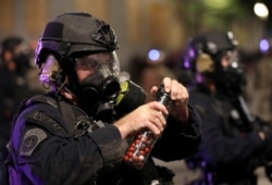 A federal law enforcement officer holds pepper balls during a protest against racial inequality and police violence in Portland, Oregon, July 28, 2020.