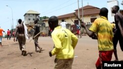 FIILE - Opposition protesters carry sticks as they march along a street in Conakry, May 2013.