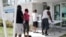 In this April 8, 2020 photo, restaurant worker Glen Pile, left, waits in line to get an unemployment form at a Miami-Dade County library during the coronavirus pandemic in Miami.