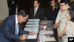 Cambodia's Prime Minister Hun Sen, left, registers before a meeting at National Assembly, in Phnom Penh, Cambodia, Monday, Feb. 20, 2017. Cambodia's legislature has approved amending a law governing political parties that would allow the government to app