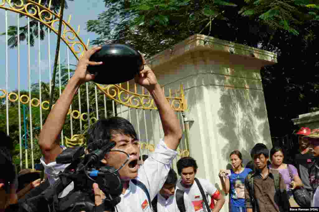 A demonstrator in front of Yangon University holds a monk's bowl upside down, a symbol of opposition.