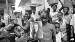 FILE - A girl holds a portrait of US President Jimmy Carter in a market in Lagos, Nigeria, March 31, 1978, the day of his arrival for a state visit, the first to Africa by an American president. 