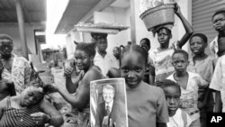 FILE - A girl holds a portrait of US President Jimmy Carter in a market in Lagos, Nigeria, March 31, 1978, the day of his arrival for a state visit, the first to Africa by an American president. 