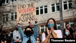 Dawn Cheung y Victoria Do aplauden durante una protesta de la Coalición organizadora de isleños del Pacífico asiático-americanos contra el odio y la discriminación, en el distrito Chinatown-International de Seattle, Washington, el 13 marzo de 2021.