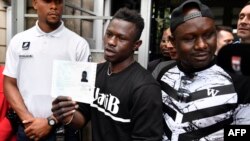 Le migrant malien Mamoudou Gassama avec son frère aîné, détient son permis de séjour temporaire après l'avoir reçu à la Préfecture de Bobigny, au nord-est de Paris, le 29 mai 2018.