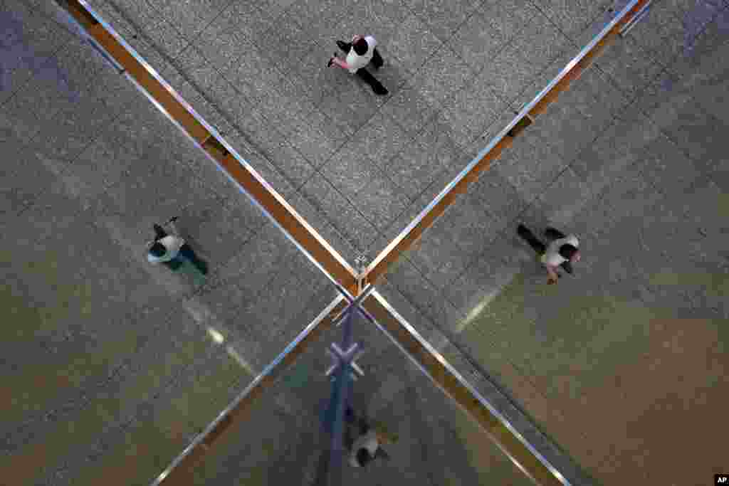 A man wearing a face mask to help curb the spread of the coronavirus is reflected on a glass wall at a shopping arcade in Tokyo.