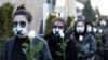 Women in black clothing with their mouths sealed with a tape walk down the street with white roses in Minsk as they protest against the verdict against the Belarusian journalist and doctor who were sentenced to jail for disclosing the medical records of a protester who died after being detained.&nbsp;