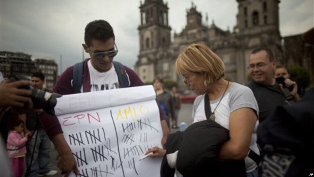 Seorang karyawan situs berita Meksiko menyelenggarakan jajak pendapat pemilu presiden untuk mencari siapa yang terunggul antara capres Andres Manuel Lopez Obrador (kanan) dan Enrique Pena Nieto, di Lapangan Zocalo di Mexico (29/6).