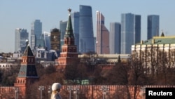 ARCHIVO - Una mujer camina por un puente, con el centro de negocios Moscow City y la muralla del Kremlin al fondo, en un día soleado en Moscú, Rusia, el 24 de febrero de 2025. 