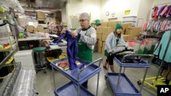 In this Friday, Dec. 21, 2018, photo, Chris Meyer, left, and Maddi Heim, fold and sort donated clothes at Treehouse, a nonprofit organization in Seattle that serves the needs of children in the foster-care system.