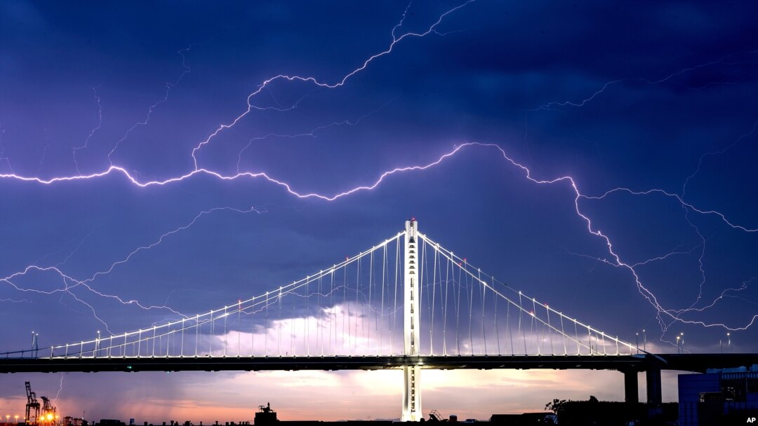 Petir di atas langit Jembatan San Francisco-Oakland Bay Bridge dibawa oleh badai yang melintas di Oakland, California, 16 Agustus 2020.