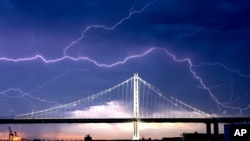 Lightning forks over the San Francisco-Oakland Bay Bridge as a storm passes over Oakland, California, Aug. 16, 2020. Numerous lightning strikes early Sunday sparked brush fires throughout the region.