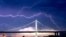 Petir di atas langit Jembatan San Francisco-Oakland Bay Bridge dibawa oleh badai yang melintas di Oakland, California, 16 Agustus 2020.