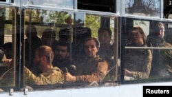 Một chiếc xe buýt chở các thành viên của lực lượng vũ trang Ukraine, những người đã đầu hàng tại nhà máy thép Azovstal bị bao vây, lái đi dưới sự hộ tống của quân đội thân Nga, ở Mariupol, Ukraine, ngày 20 tháng 5 năm 2022.