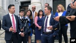 Attorneys Joshua Koskoff, left, and Christopher Mattei, right, representing parents, rear, of children killed in the 2012 Sandy Hook Elementary School shooting, speak outside the Connecticut Supreme Court, Sept. 26, 2019