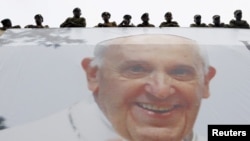 Du dessus d'une affiche au visage du pape François, des officiers de l'armée kényane assistent à une messe qu'il célèbre à Nairobi, au Kenya, le 26 novembre 2015. (Photo REUTERS/Stefano Rellandini) 