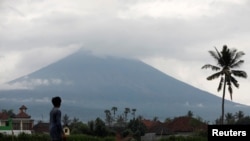 Seorang petani melihat ke arah Gunung Agung, yang menyemburkan asap dan abu, dekat Amed, Kabupaten Karangasem, Bali, Indonesia, 30 November 2017.